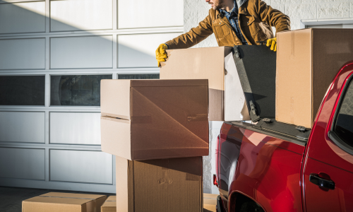 A farmer loading boxes into the back of a pickup truck.