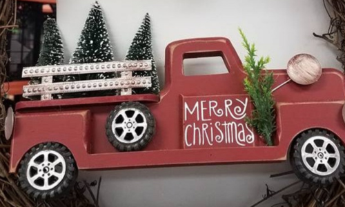 A Christmas decor pickup truck carrying pine trees.