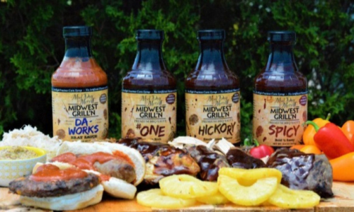 Hot sauce in a bottle on display, surrounded by an array of fruit.